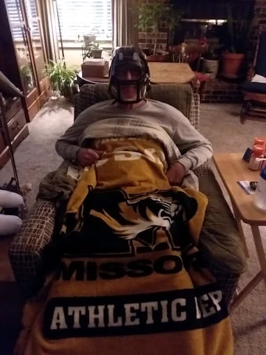 Person relaxing at home wrapped in yellow and black Athletic blanket