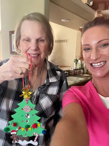 Two women smiling together, one wearing festive Christmas tree sweater